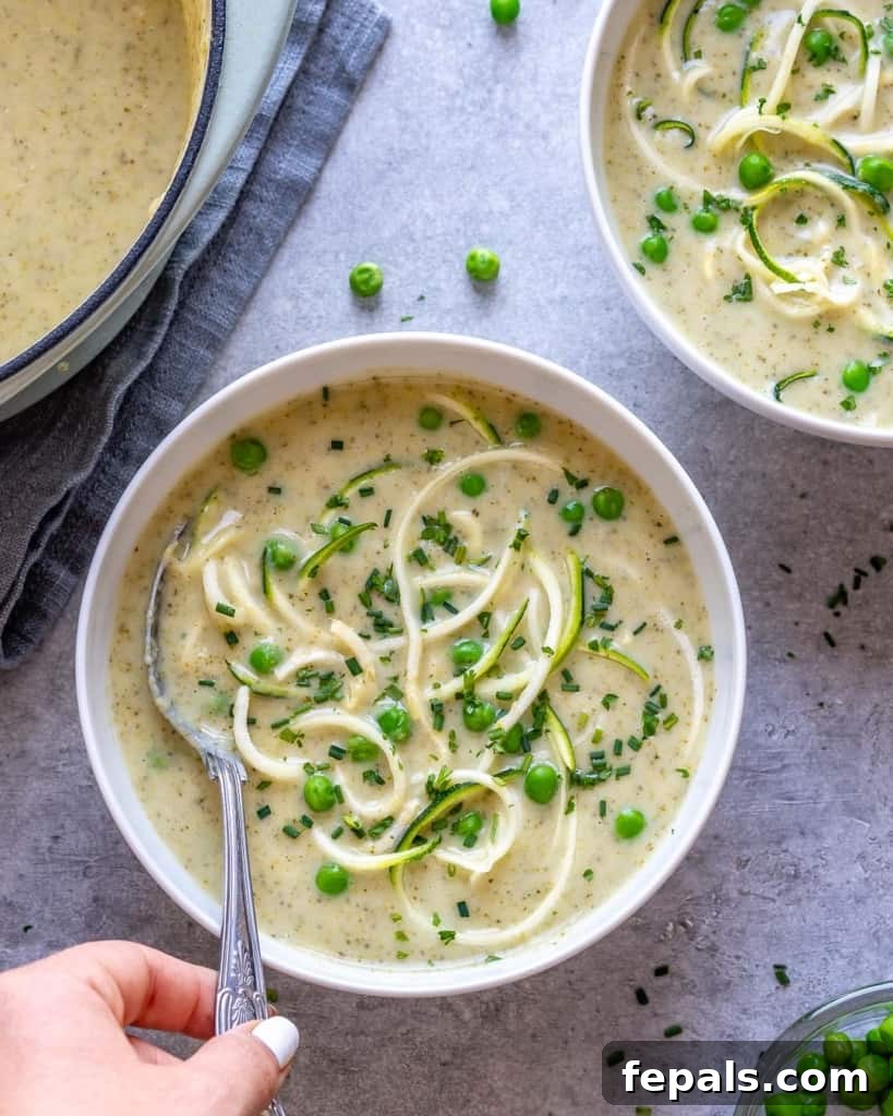 hand holding spoon in bowl of zucchini and broccoli soup
