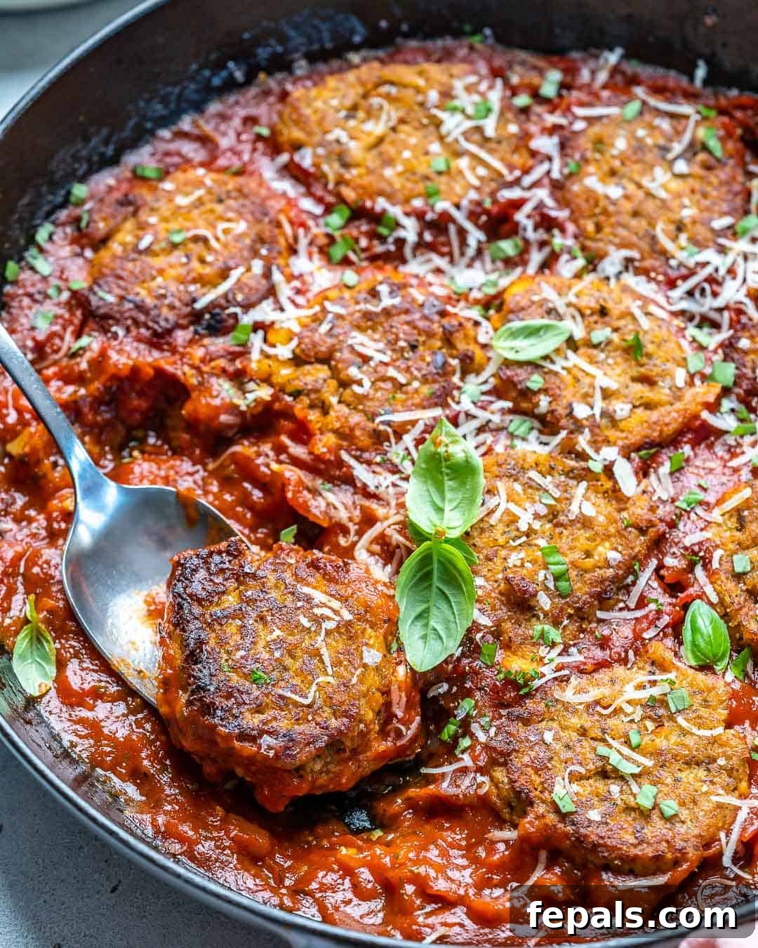 Savory Garden Meatballs 5 A spoonful of vegetarian meatballs generously coated in rich red marinara sauce, served in a black skillet.