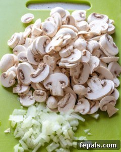 Savory Garden Meatballs 7 Sliced mushrooms and onions on a cutting board, prepped for cooking.