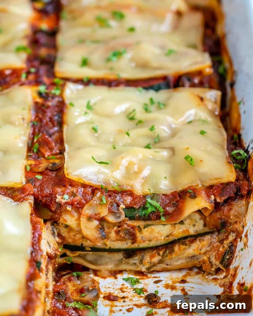A full baking dish of sliced vegan zucchini lasagna, showing its appetizing layers and golden, bubbly top, ready to be served at a family meal.
