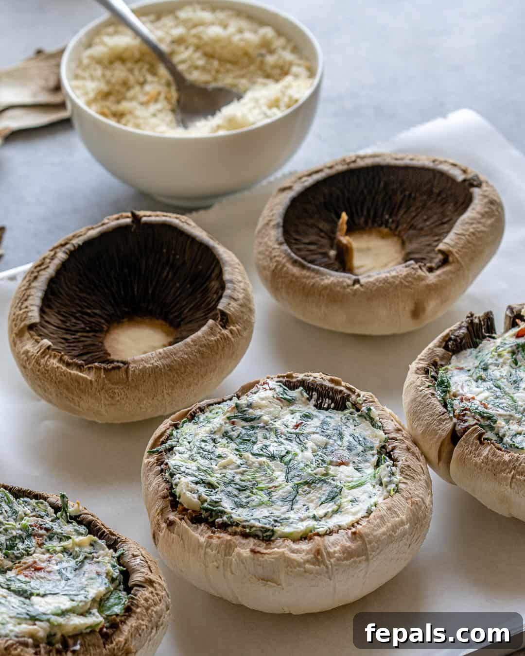Rustic Tuscan Stuffed Mushrooms 6 A pair of hands carefully spooning the creamy Italian-flavored stuffing into the hollowed-out caps of portobello mushrooms on a baking sheet, preparing them for baking.