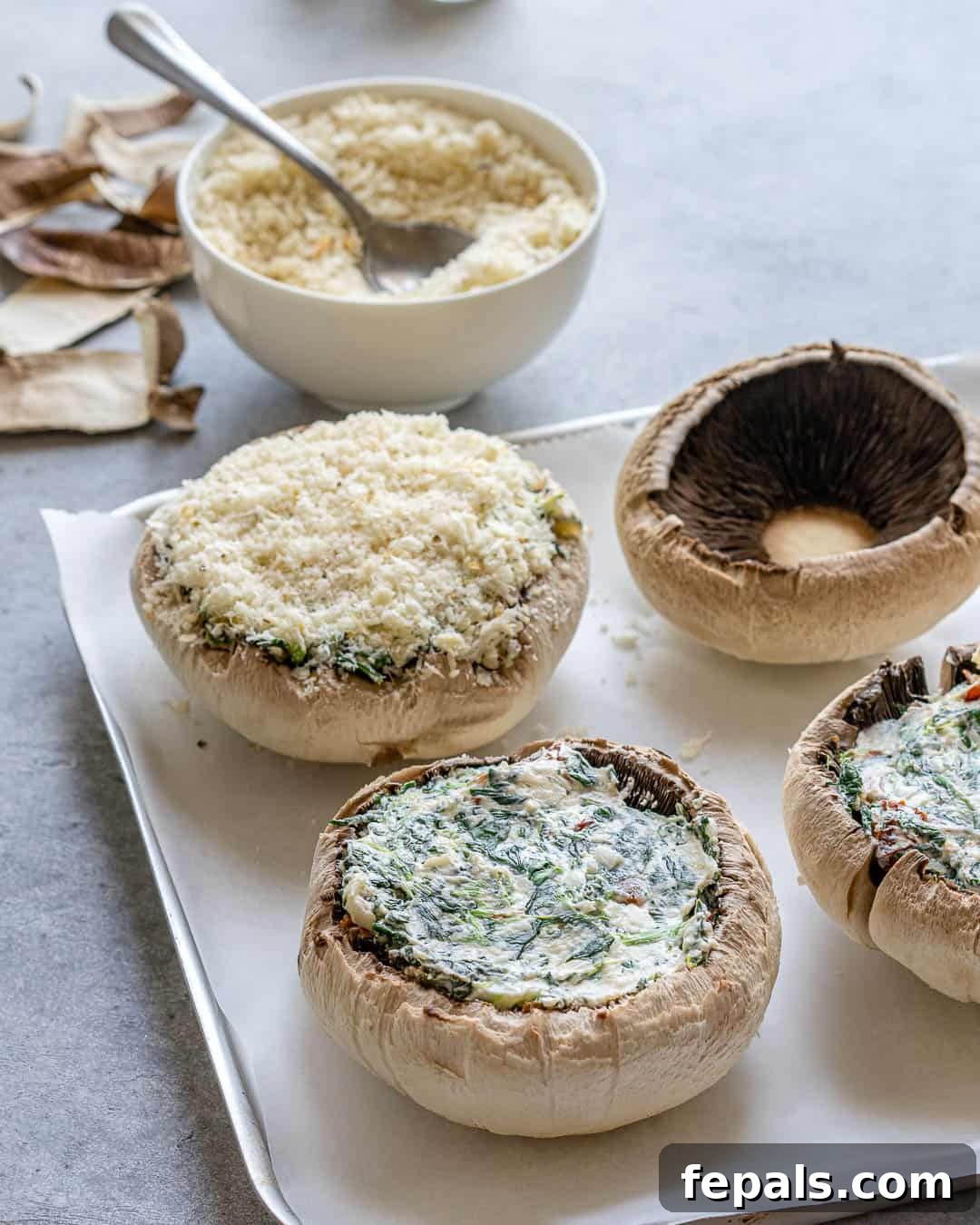Rustic Tuscan Stuffed Mushrooms 7 A close-up of stuffed portobello mushrooms on a baking sheet, with a generous layer of panko breadcrumbs and parmesan cheese sprinkled over the filling, ready for the oven.