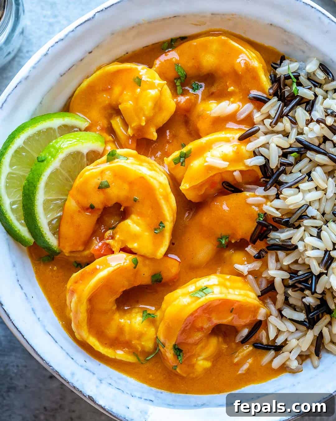 Creamy Coconut Shrimp Curry 7 A beautifully presented bowl of shrimp curry served with cooked rice, garnished with fresh cilantro and a lime wedge
