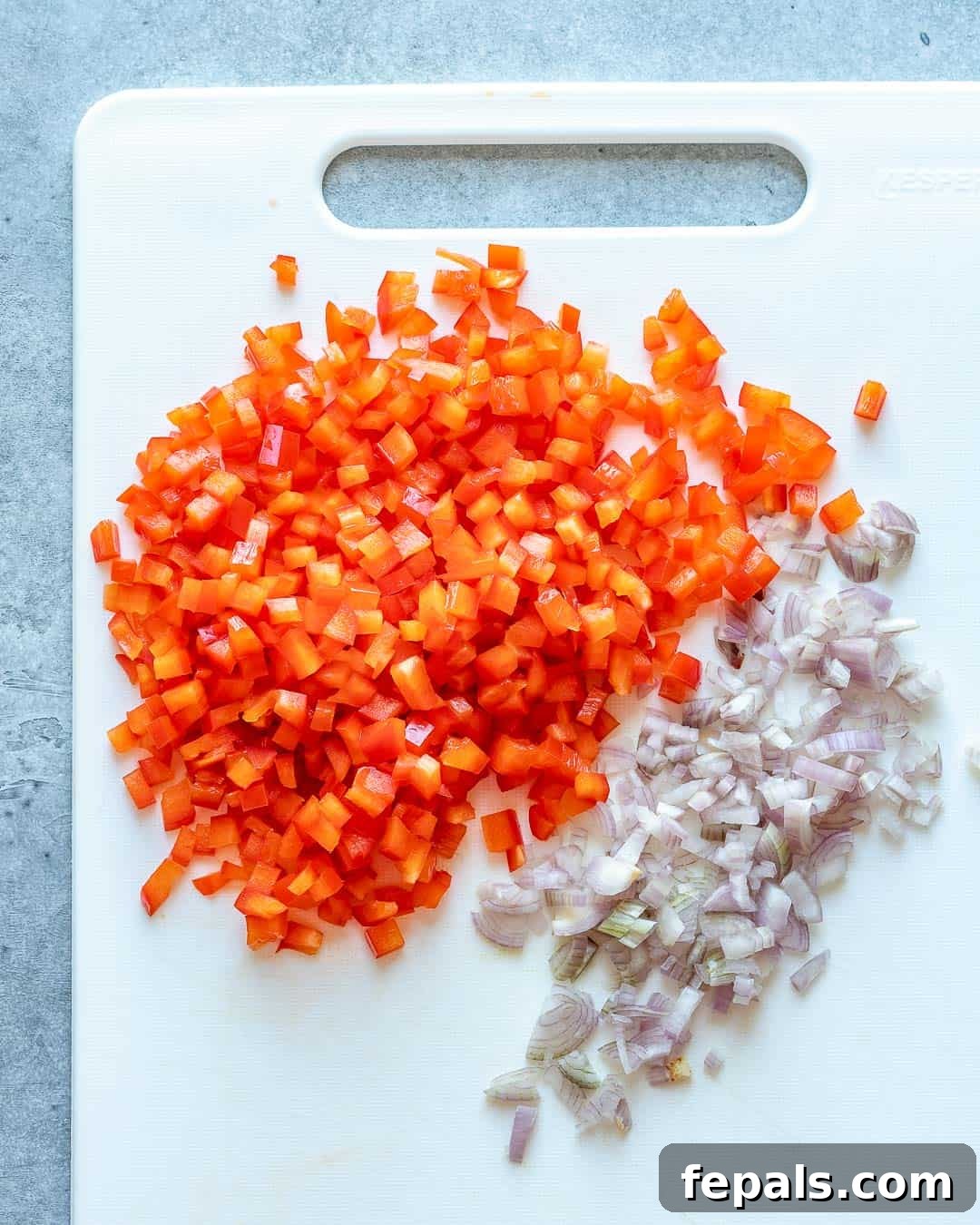 Bell pepper and onion chopped on cutting board