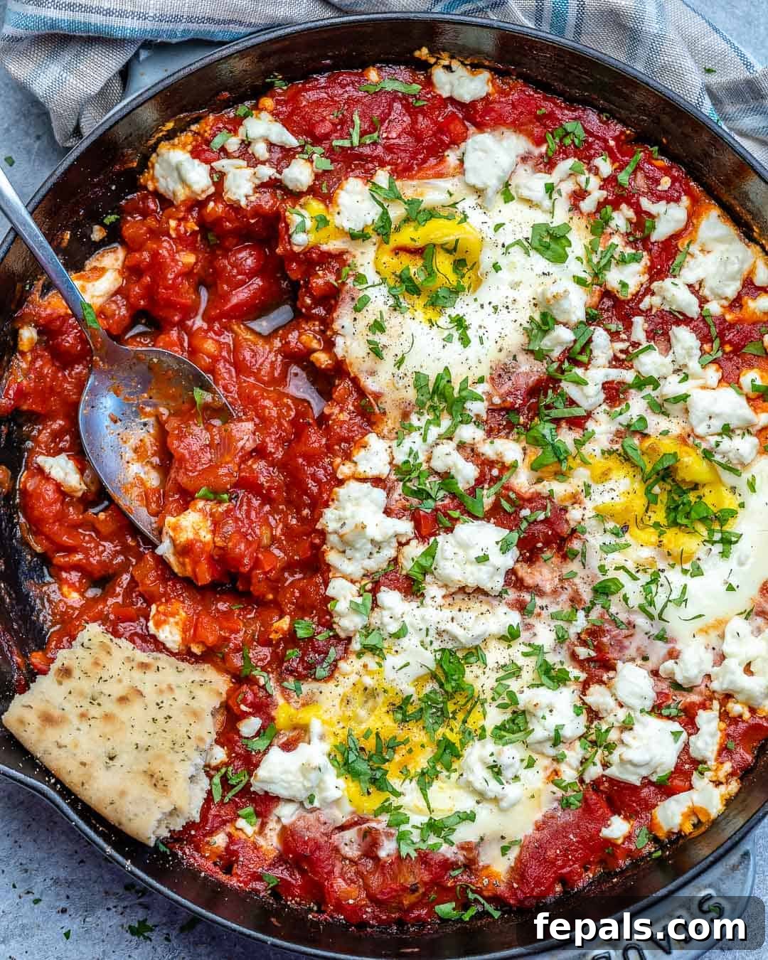 Top view of easy shakshuka with feta with spoon in skillet