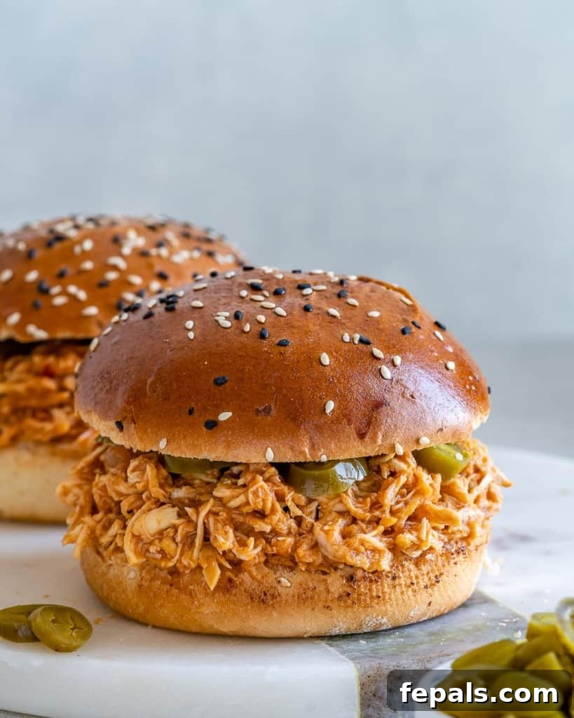 Two pulled chicken burgers on white surface
