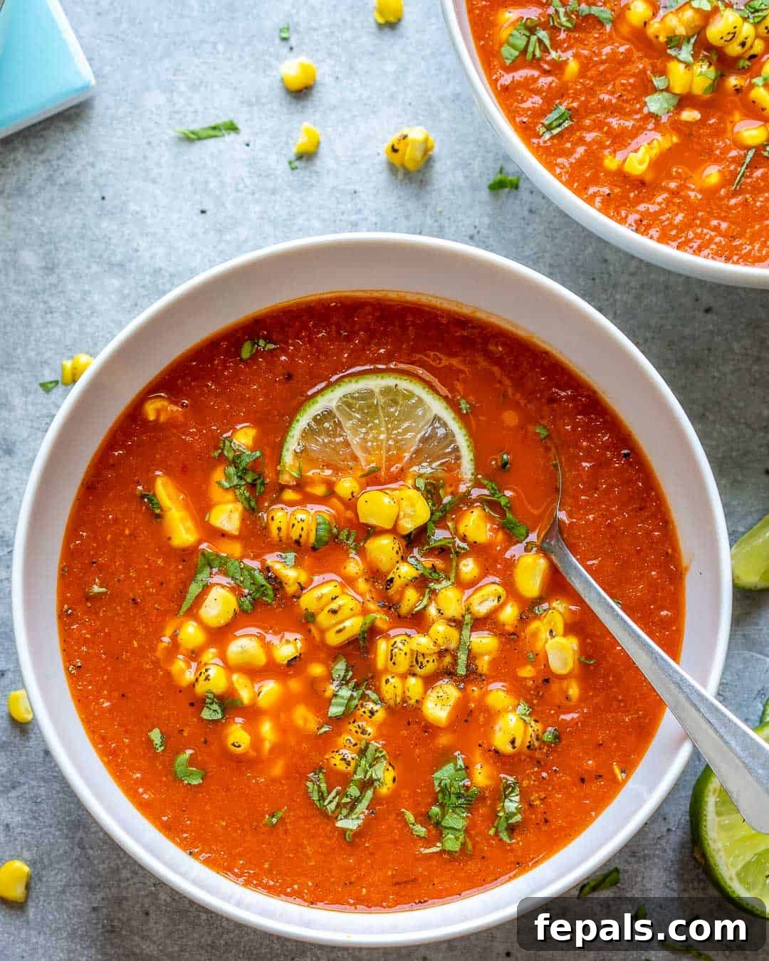 Creamy Mexican Street Corn Soup 8 A single white bowl of Mexican Sweet Corn Soup, adorned with fresh lime and cilantro, a spoon resting beside it, inviting a tasting.
