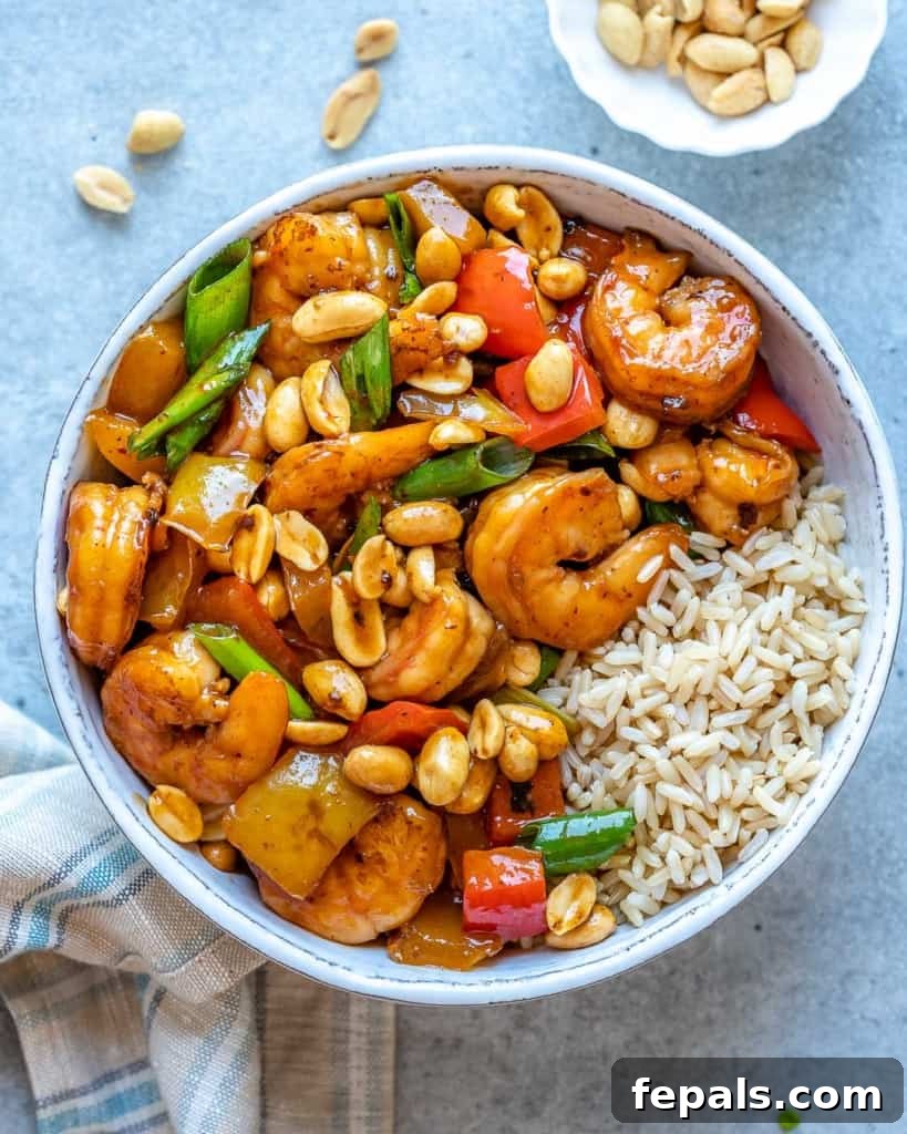 Top view of kung pao shrimp in white bowl with rice
