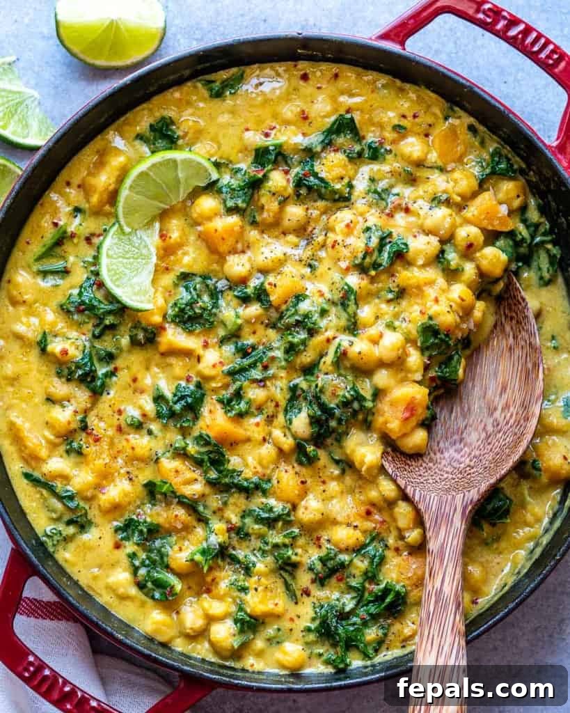 top view of wooden spoon in butternut curry in a skillet