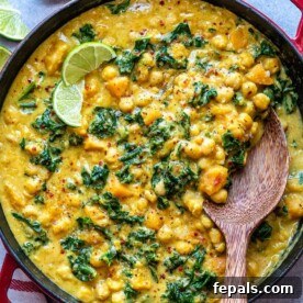 top view of wooden spoon in butternut curry in a skillet