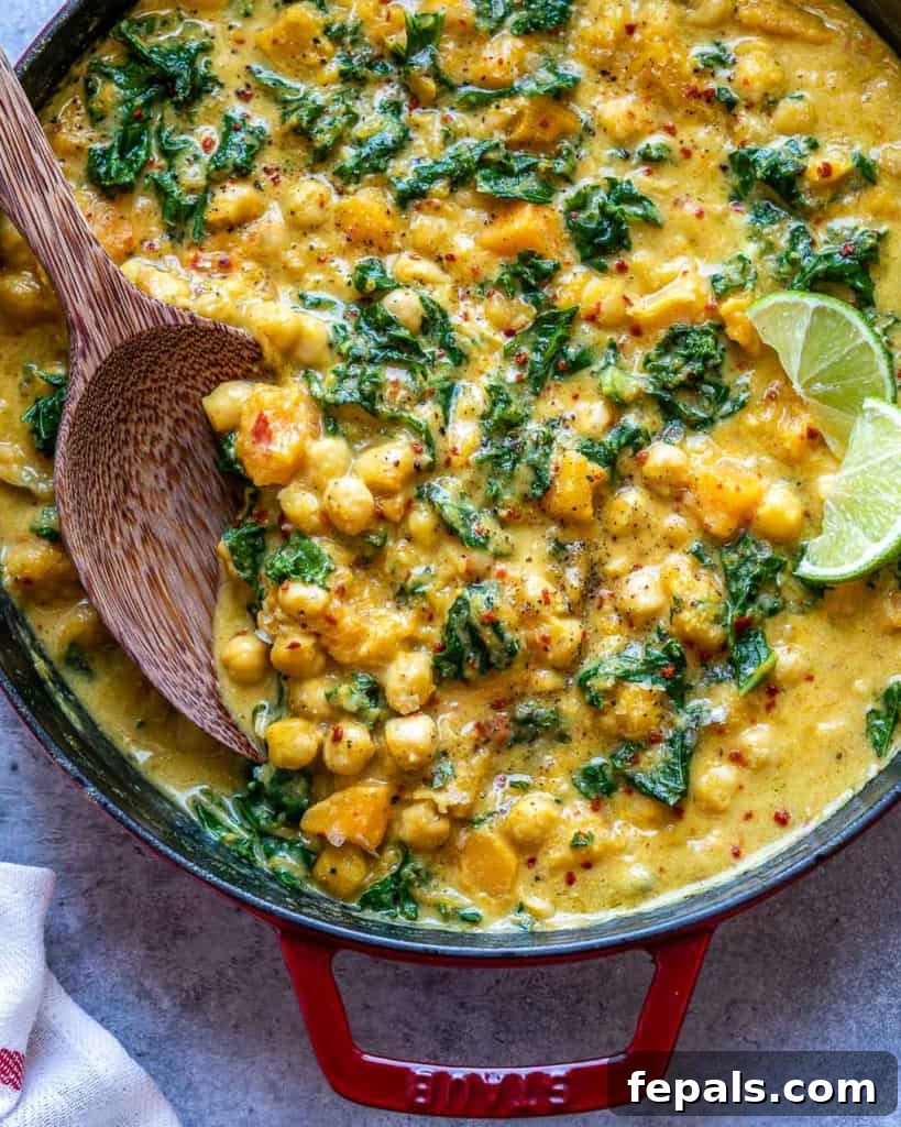 Overhead shot of chickpea butternut squash curry being stirred in a pot.