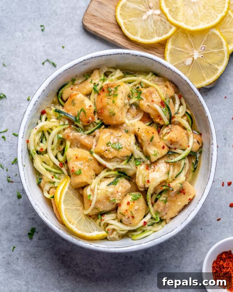 chicken scampi and zoodles in a white bowl with lemon slices on the side 