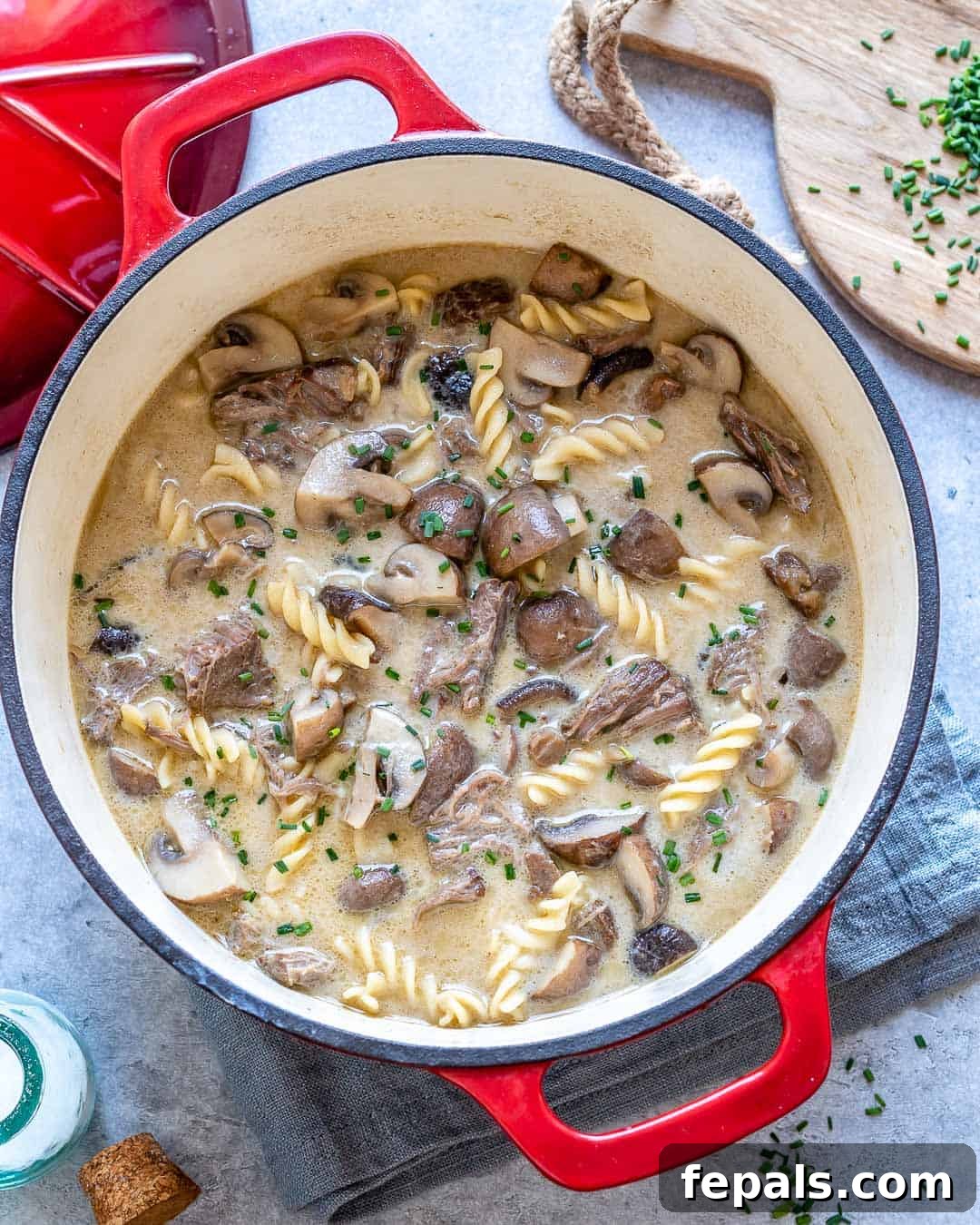 Heartwarming Beef Stroganoff Soup 8 Pot of beef stroganoff soup with red towel and chopped herbs on counter