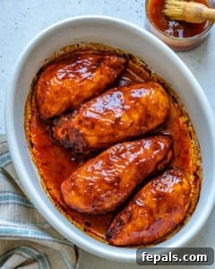 Glazed BBQ Chicken Breast 8 Top view of white baking dish with 4 Baked BBQ Chicken Breasts and bowl of BBQ sauce on side
