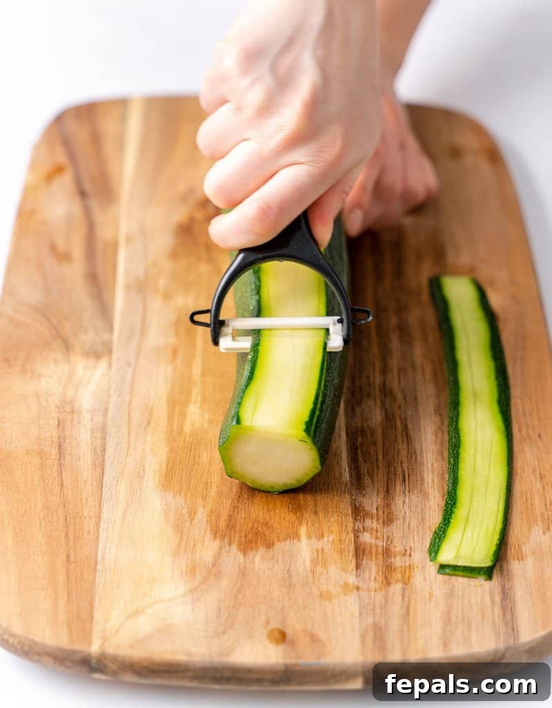 Simple Steps to Homemade Zucchini Noodles 13 a hand holding a julienne peeler, peeling a thin layer of zucchini