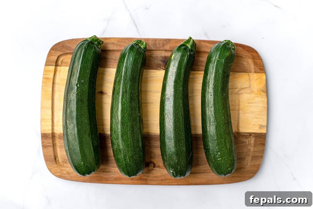 Simple Steps to Homemade Zucchini Noodles 18 four green zucchinis on a brown cutting board, showcasing their vibrant color