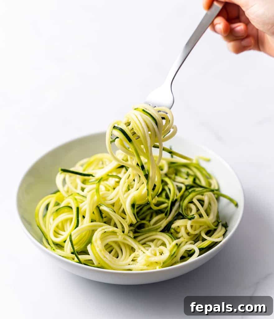 Simple Steps to Homemade Zucchini Noodles 19 a hand holding a fork, expertly twirling zoodles from a pristine white plate, invitingly ready to eat