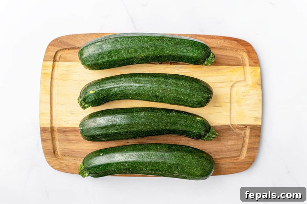 Simple Steps to Homemade Zucchini Noodles 3 4 whole green zucchinis on a brown cutting board, ready for spiralizing