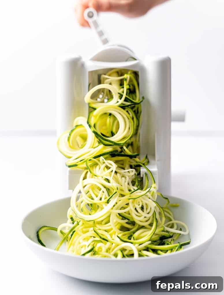 Simple Steps to Homemade Zucchini Noodles 4 using a spiralizer to create zucchini noodles directly onto a white plate