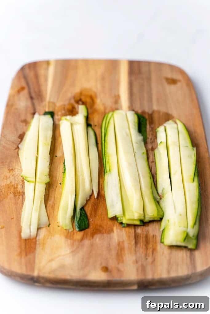 Simple Steps to Homemade Zucchini Noodles 10 layers of freshly cut zucchini noodles neatly arranged on a cutting board
