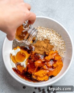 pouring maple syrup in a bowl with ingredients for pumpkin overnight oats
