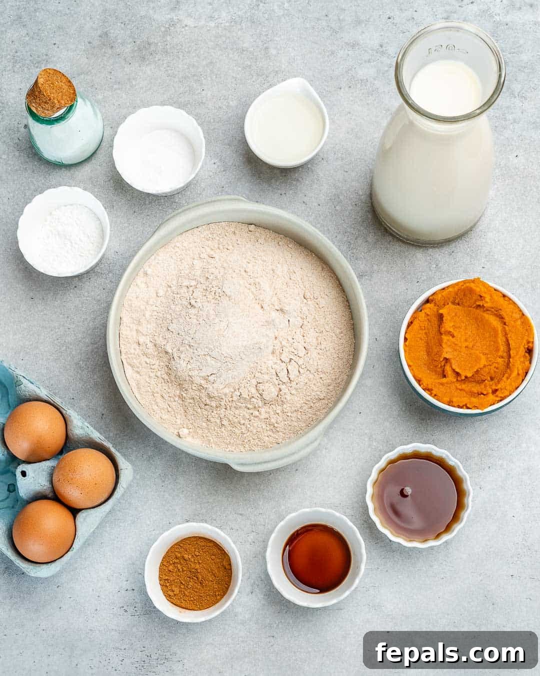 Wholesome Pumpkin Waffles 4 A collection of ingredients neatly laid out for making pumpkin waffles, including flour, pumpkin puree, eggs, spices, and oil.