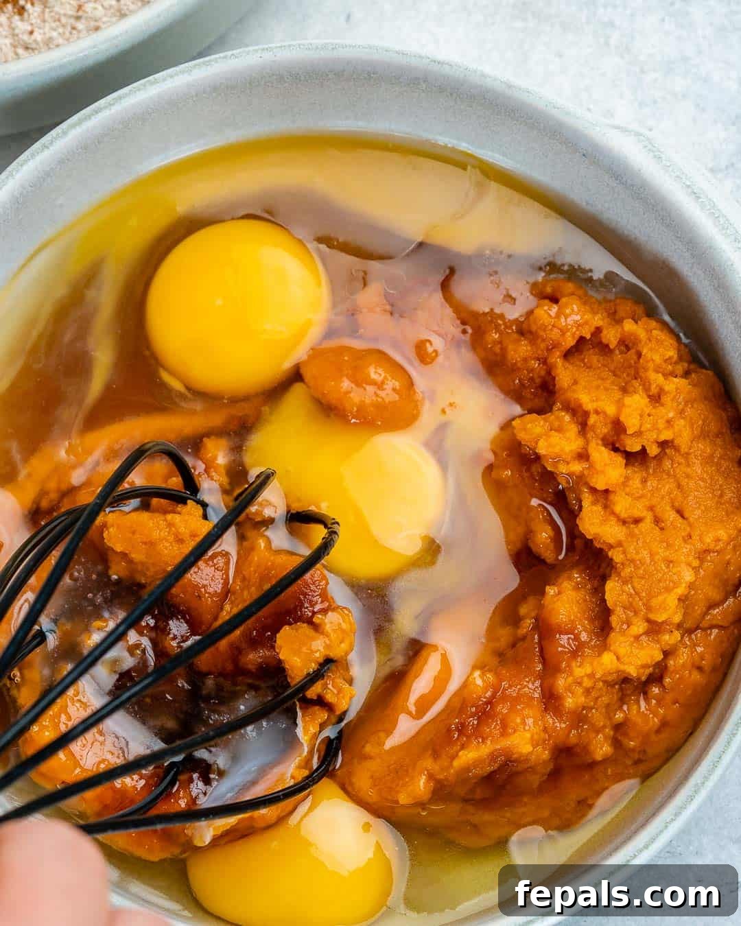 Wholesome Pumpkin Waffles 5 A bowl containing pumpkin puree, melted coconut oil, and whisked eggs, ready to be combined.