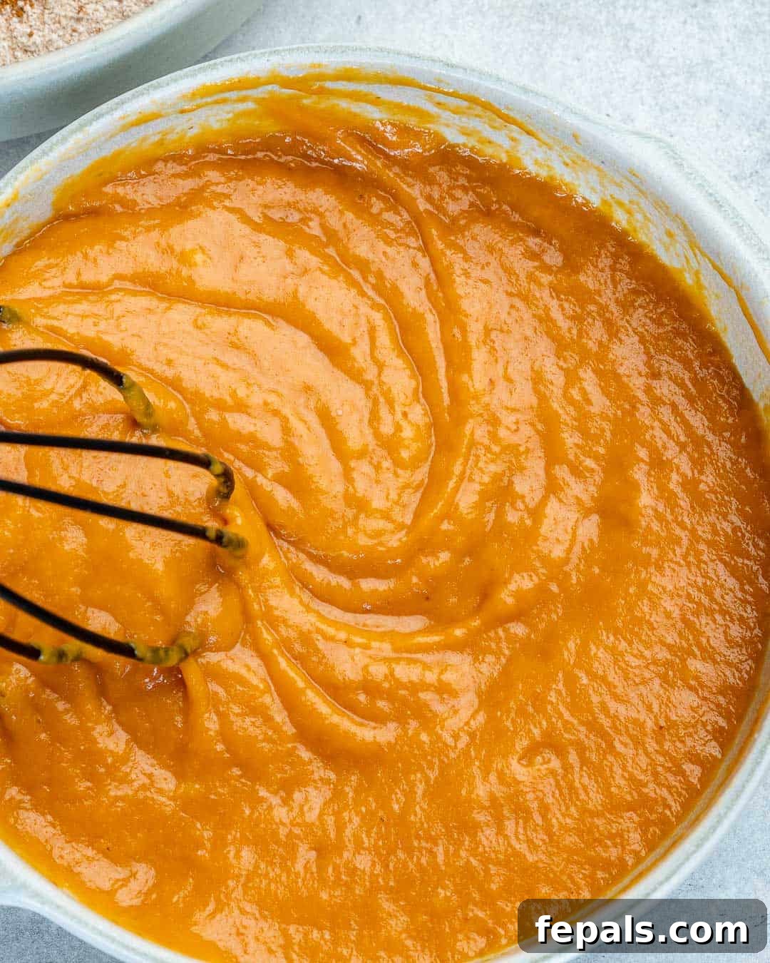 Wholesome Pumpkin Waffles 6 Pumpkin puree and eggs beautifully whipped together in a bowl, creating a smooth and creamy mixture.