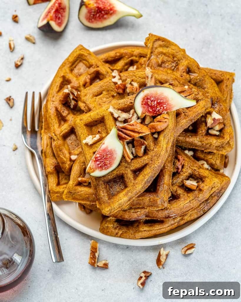 Wholesome Pumpkin Waffles 7 A fork resting next to a perfectly cooked, golden-brown pumpkin waffle on a white plate, inviting you to take a bite.
