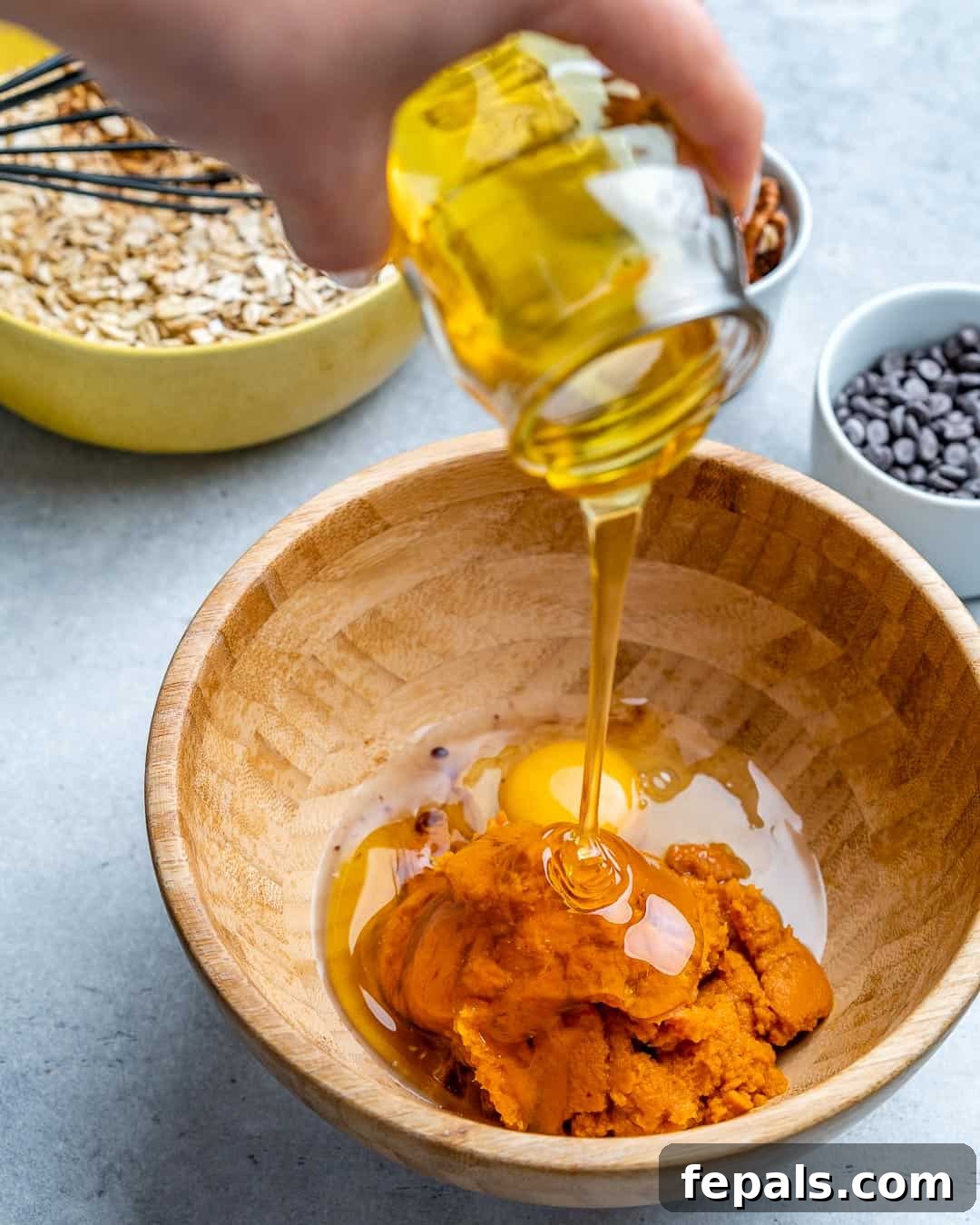 Spiced Pumpkin Chocolate Chip Breakfast Bake 5 pumpkin puree and eggs in brown bowl, honey being poured over them