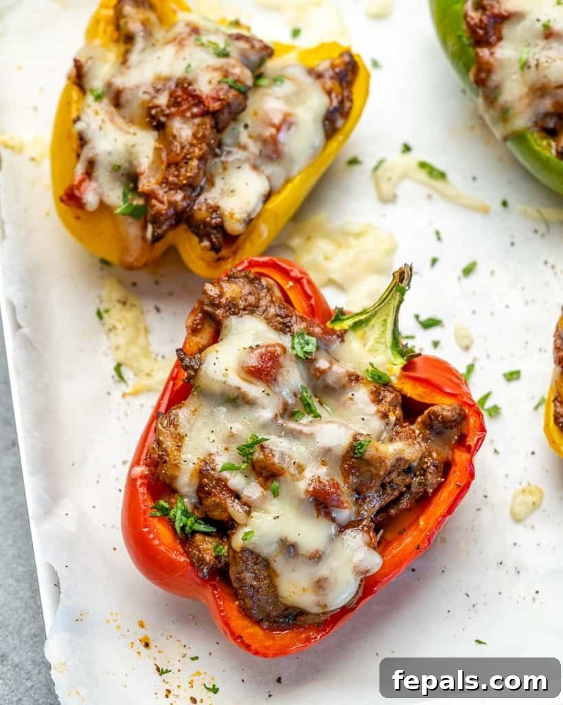 Fiesta Keto Steak Stuffed Peppers 2 Side view of vibrant stuffed peppers on a rustic plate, garnished with fresh cilantro and lime wedges.