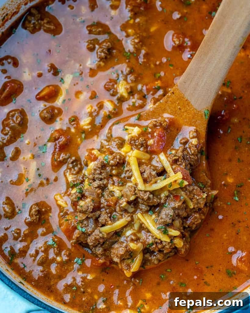 Ultimate Keto Beef Chili 7 Overhead view of chili being stirred in a pot, highlighting its rich, thick consistency.
