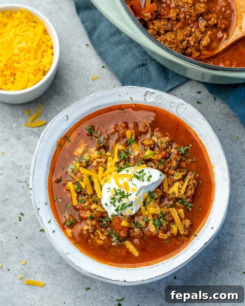 Ultimate Keto Beef Chili 10 Overhead view of a bowl of chili next to a blue pot of chili, ready for serving.