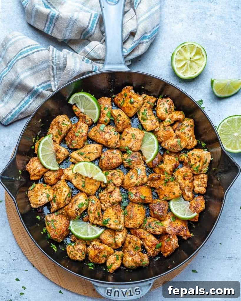 Overhead shot of freshly cooked cilantro lime chicken bites in a skillet with vibrant lime wedges