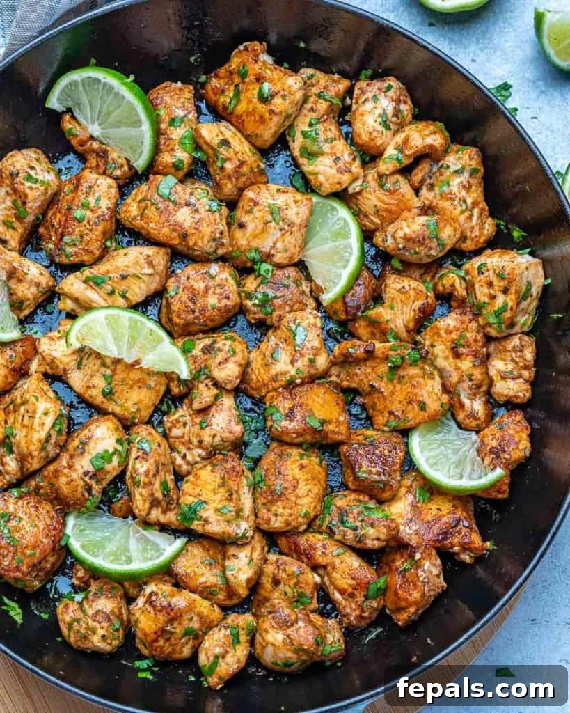Detailed top-down view of cilantro lime chicken bites with fresh lime wedges in a cast-iron skillet
