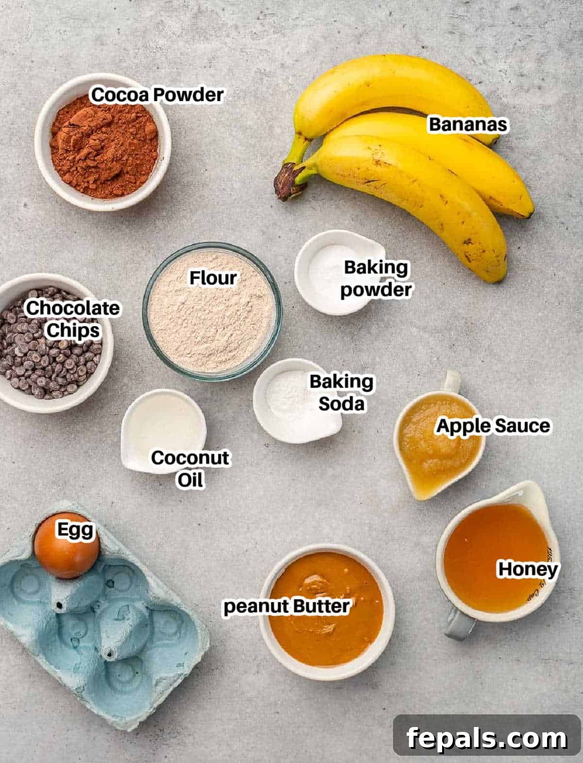 A flat lay photograph showcasing all the fresh ingredients needed to bake delicious peanut butter and chocolate muffins.