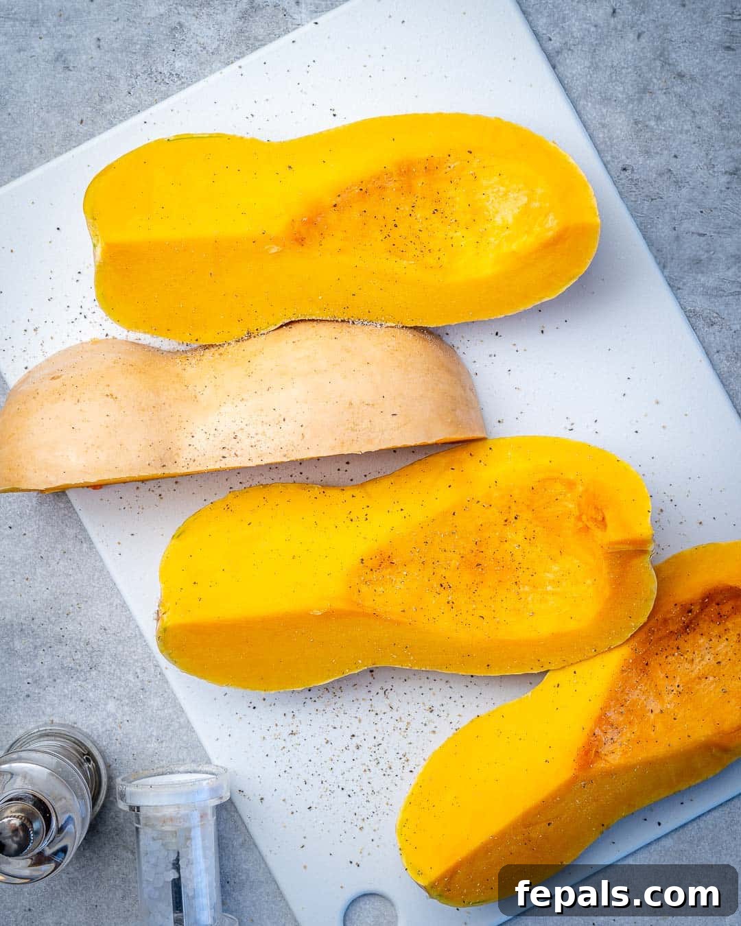 Golden Roasted Butternut 6 Prepared butternut squash cut into four wedges, seasoned and ready for the oven on a baking sheet.