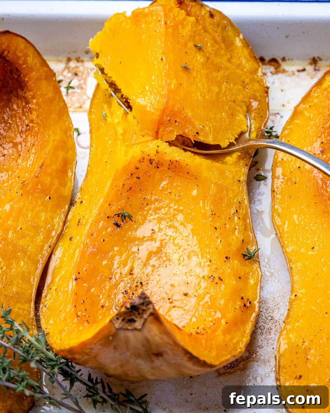 Golden Roasted Butternut 9 A spoon delicately scooping out tender, soft roasted butternut squash from its skin.