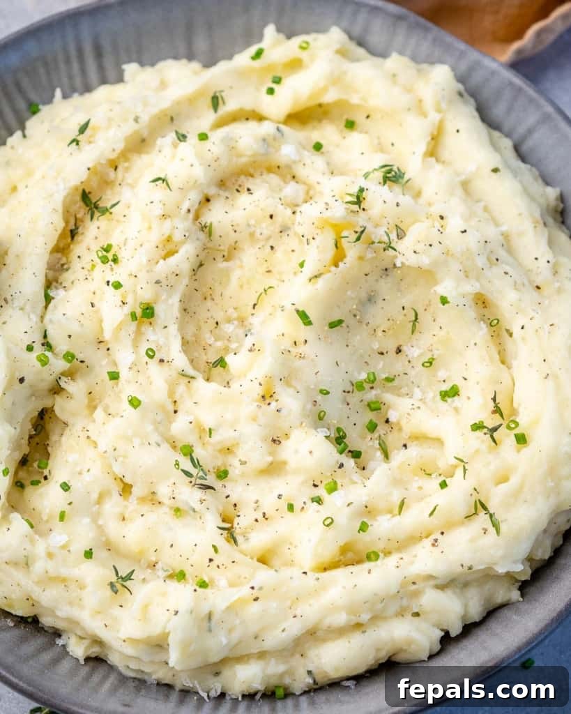 Overhead shot of healthy mashed potatoes in a bowl, garnished with fresh herbs.