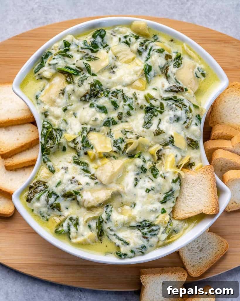 top view of spinach dip in a white bowl with slices of bread on the side