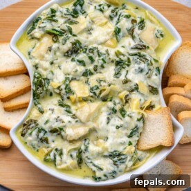 top view of spinach dip in a white bowl with slices of bread on the side.