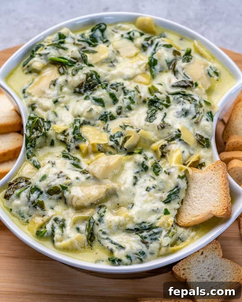 Top down shot of crockpot spinach artichoke dip in a bowl with crackers. 
