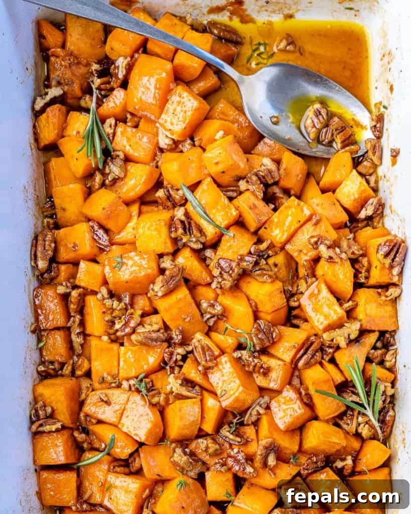 Top down view roasted sweet potatoes in a baking dish with a spoon.