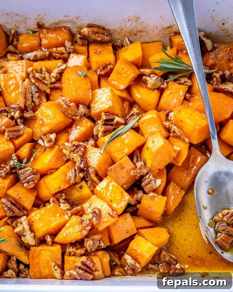 Overhead shot of maple roasted sweet potatoes in a white baking dish with a silver spoon.