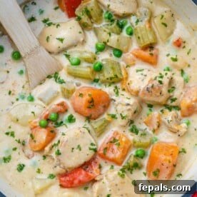 Velvety Chicken Stew 11 top view of spoon in chicken stew in pot with wooden spoon in pot