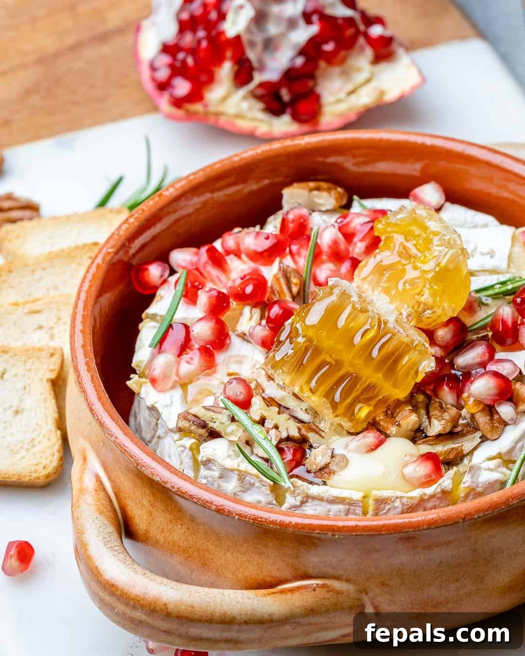 Warm Brie with Jewels of Pomegranate 9 Baked brie with pomegranates in baking dish with crackers on side
