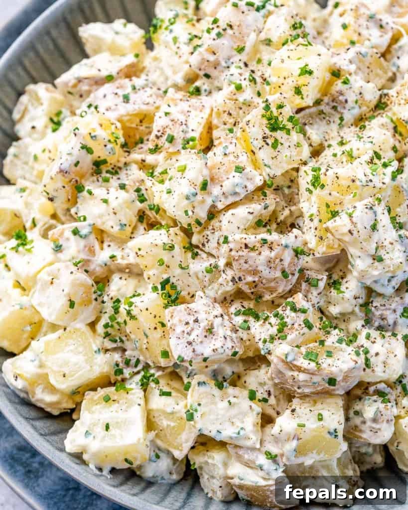 Simple Zesty Mustard Potato Salad 3 Close-up of healthy mustard potato salad garnished generously with fresh chives, showcasing the creamy texture and vibrant green herbs.