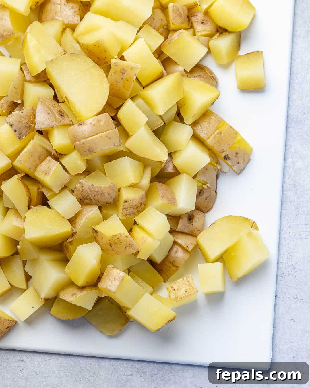 Simple Zesty Mustard Potato Salad 6 Cooked and chopped baby new potatoes on a wooden cutting board, perfectly diced and ready for mixing with the dressing.