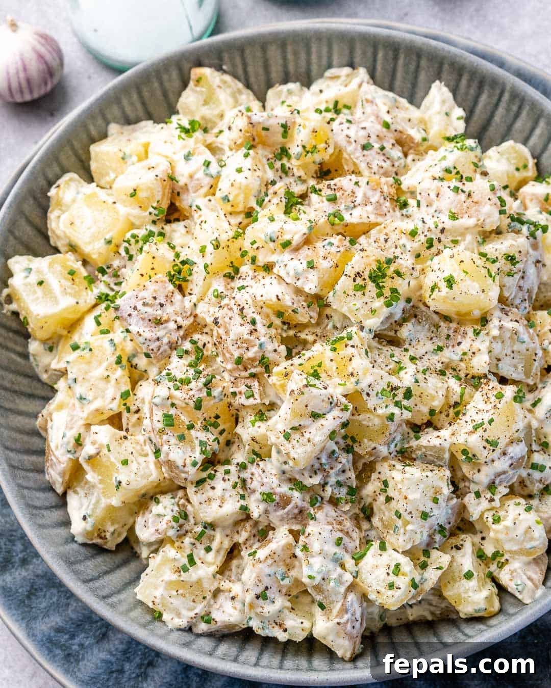 Simple Zesty Mustard Potato Salad 8 Top view of a generously filled gray bowl of easy mustard potato salad, elegantly presented with salt and pepper shakers in the background on a rustic counter.