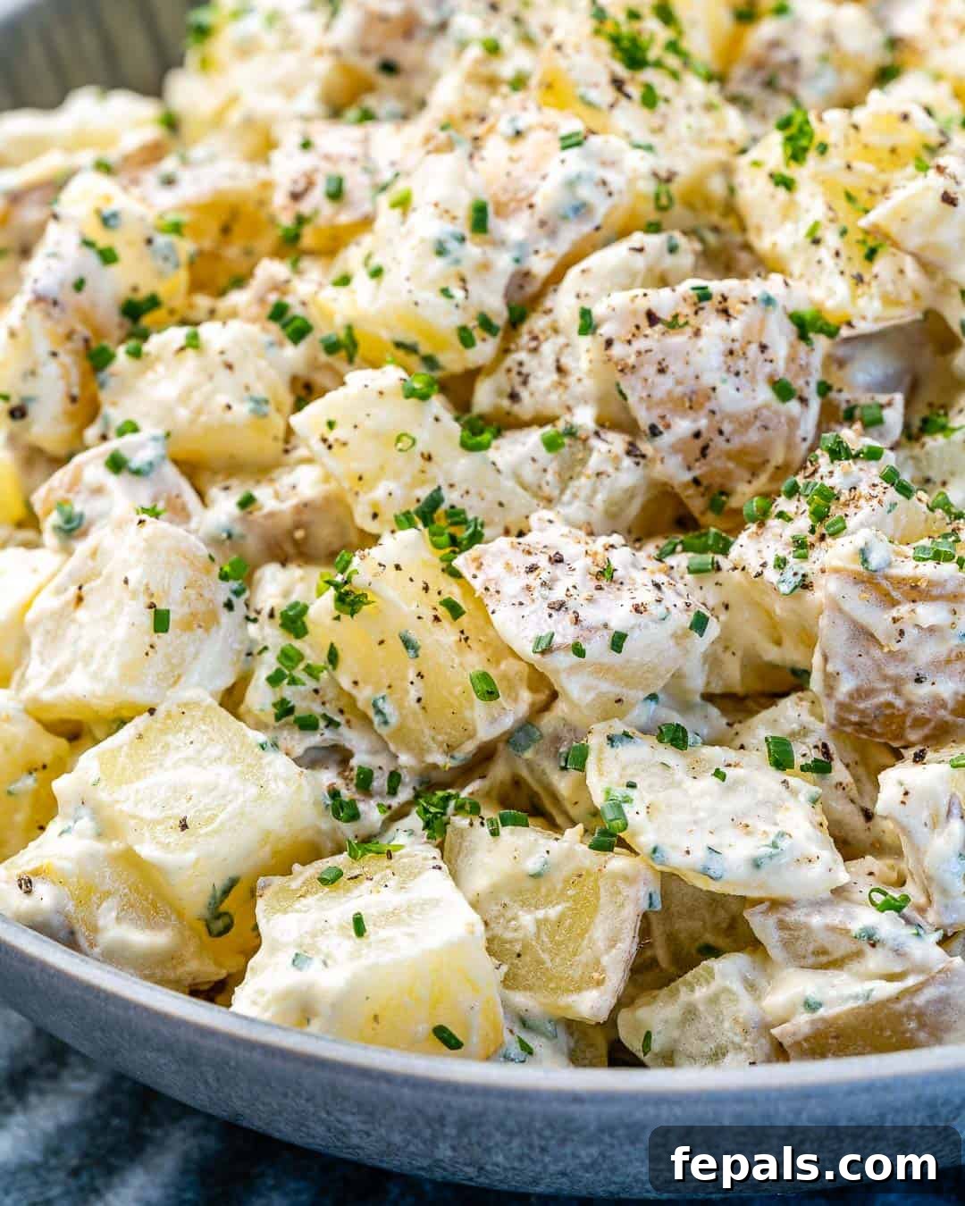 Simple Zesty Mustard Potato Salad 9 A really close-up view of the easy mustard sauce generously coating the potato salad in a gray bowl, emphasizing the creamy texture.